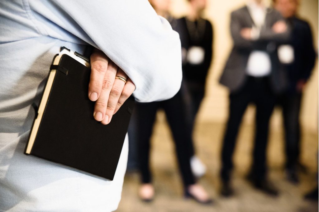 Employee holding a notebook with colleagues in the background