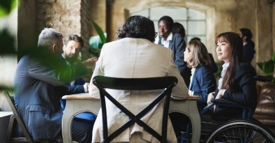 Colleagues meeting around a table, including a wheelchair user