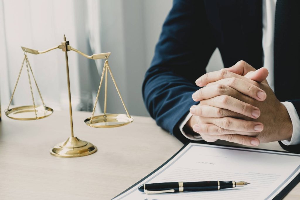Legal adviser seated beside scales of justice