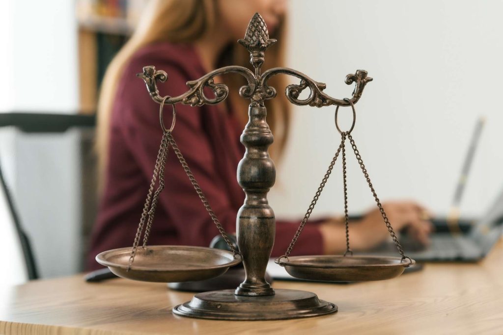 Scales of justice on a desk with a legal adviser working in the background